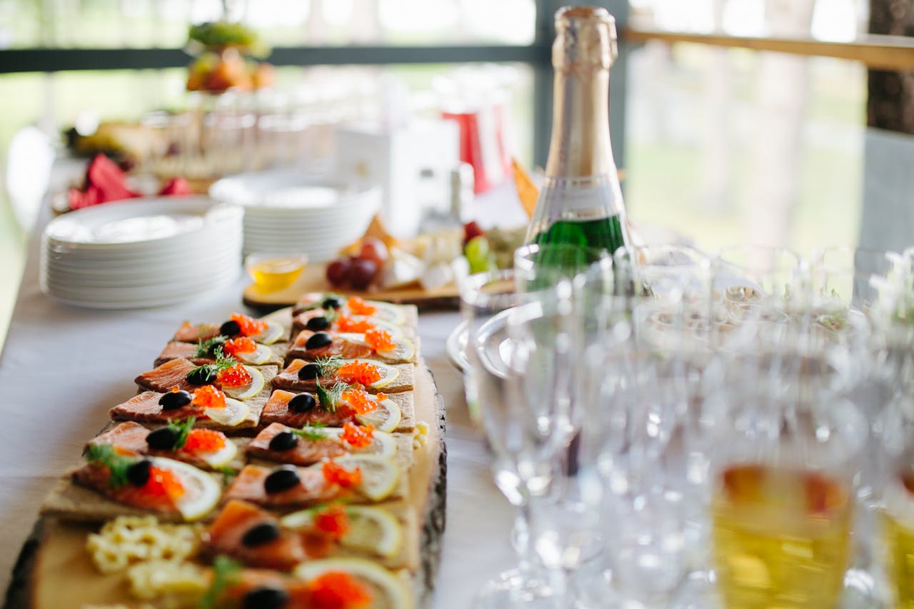 Catering Appetizers on Wooden Board Next to Empty Champagne Glasses